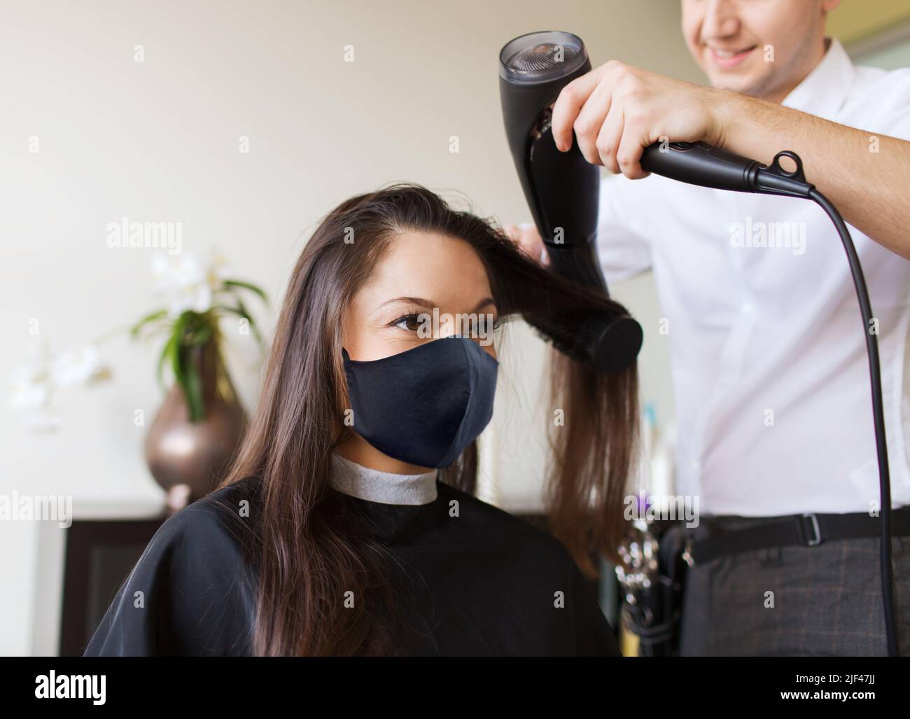 happy woman with stylist making hairdo at salon Stock Photo