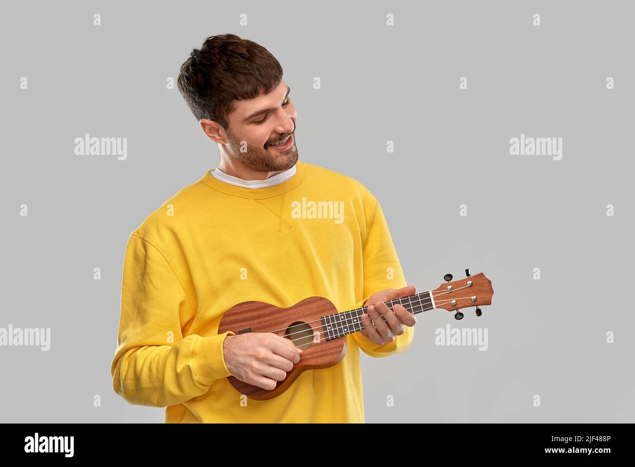 smiling young man playing ukulele guitar Stock Photo
