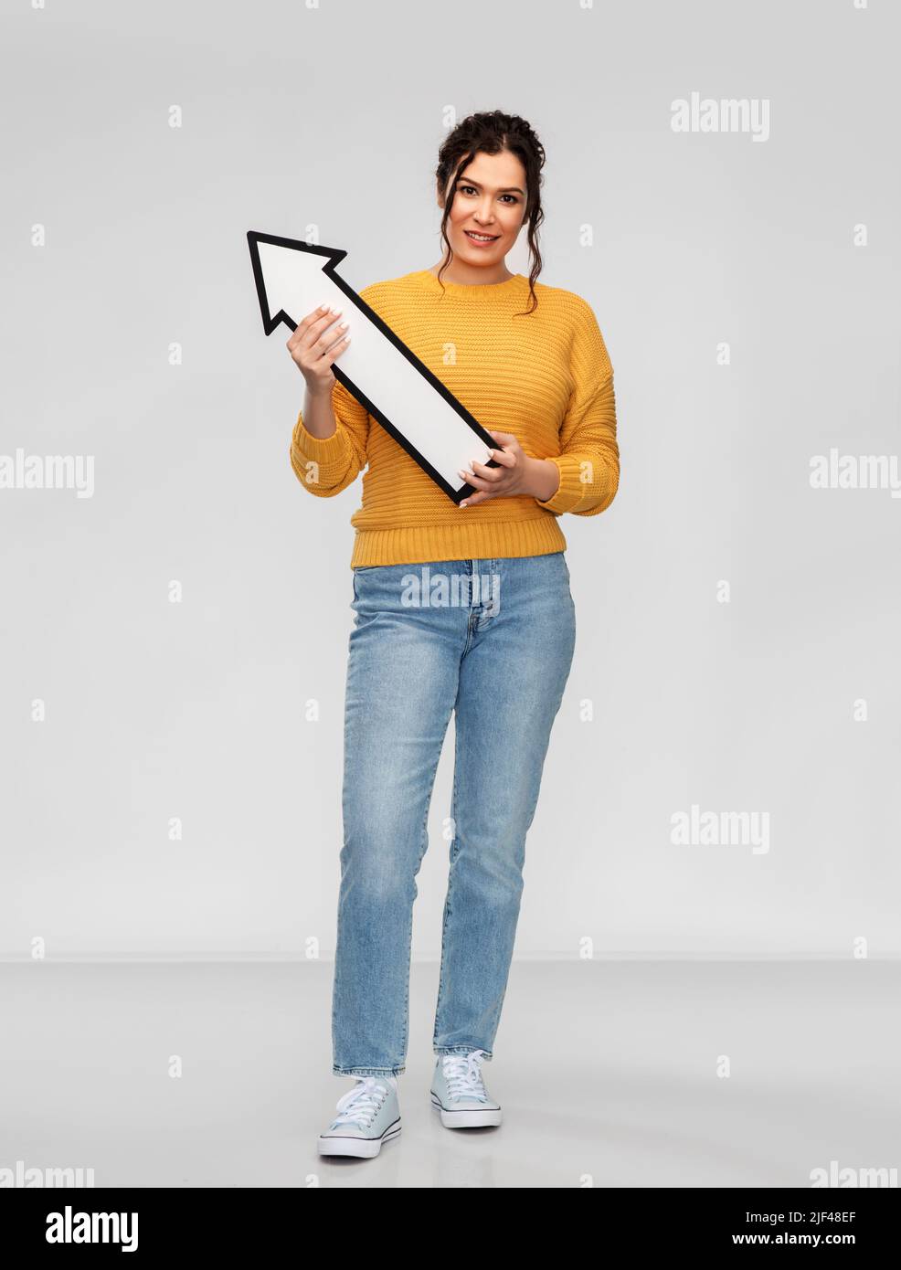 smiling young woman with big white upward arrow Stock Photo