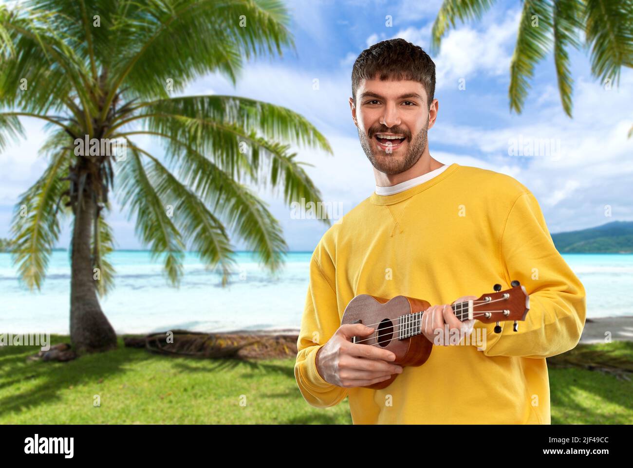 smiling young man playing ukulele guitar Stock Photo