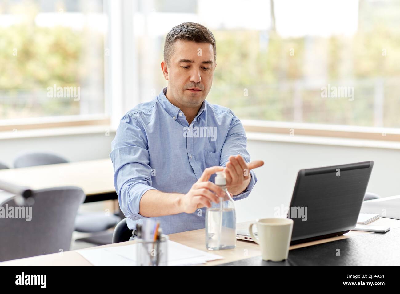 man using hand sanitizer at home office Stock Photo