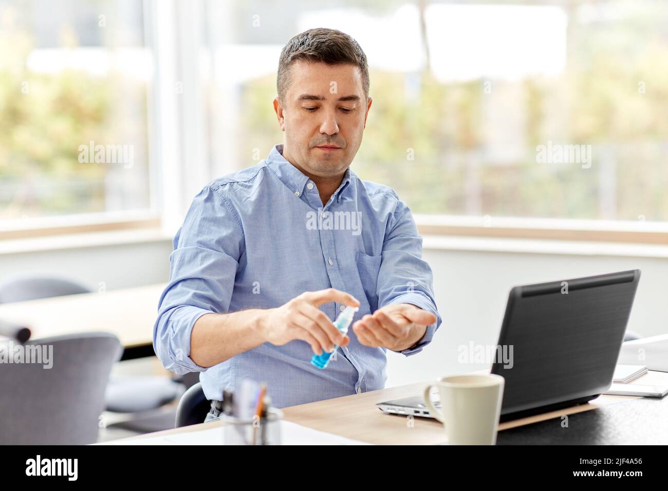 man using hand sanitizer at home office Stock Photo