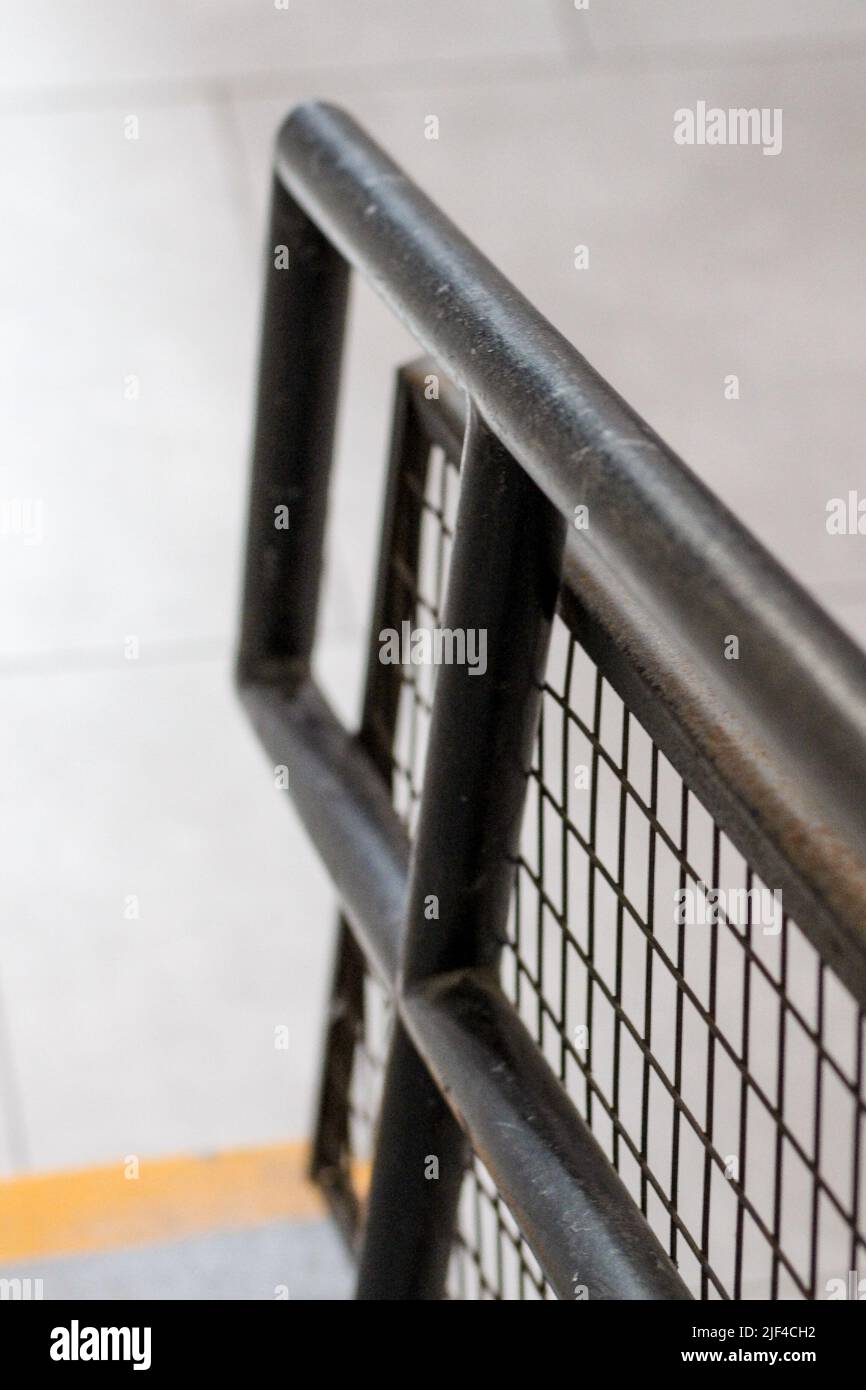 A vertical shot of a black light metal linear fence with a gray ...