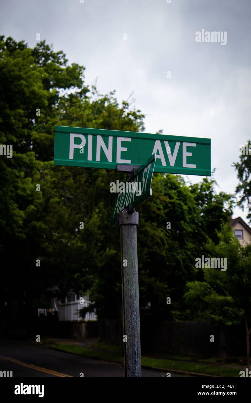 A vertical closeup of green boards with street names on a pole Stock