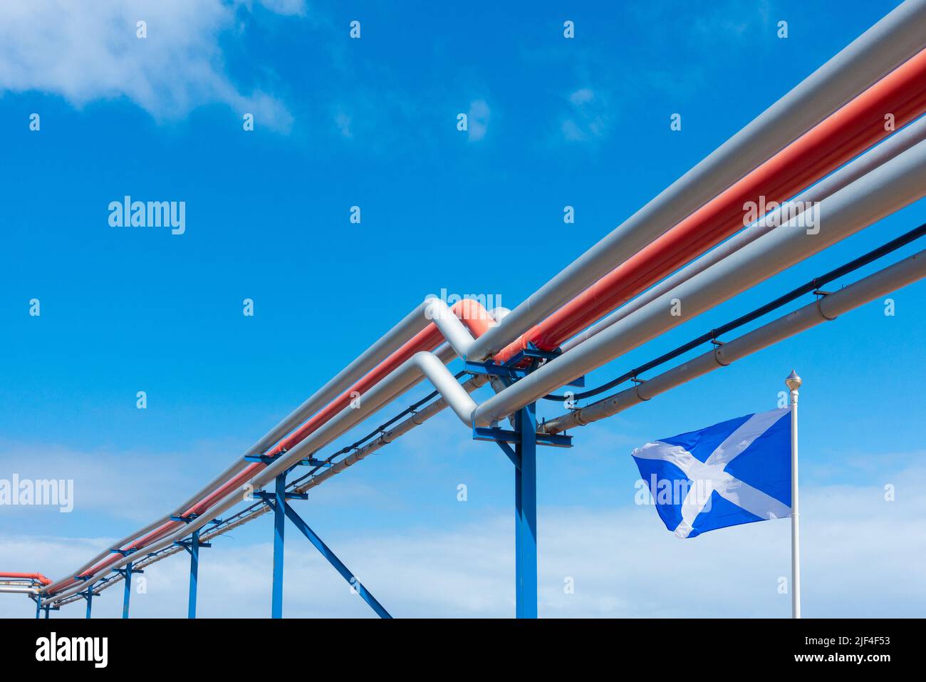 Flag of Scotland under fuel, gas, oil refinery pipes, pipeline. Fossil fuels, North Sea gas, Scottish economy, independence referendum... concept Stock Photo