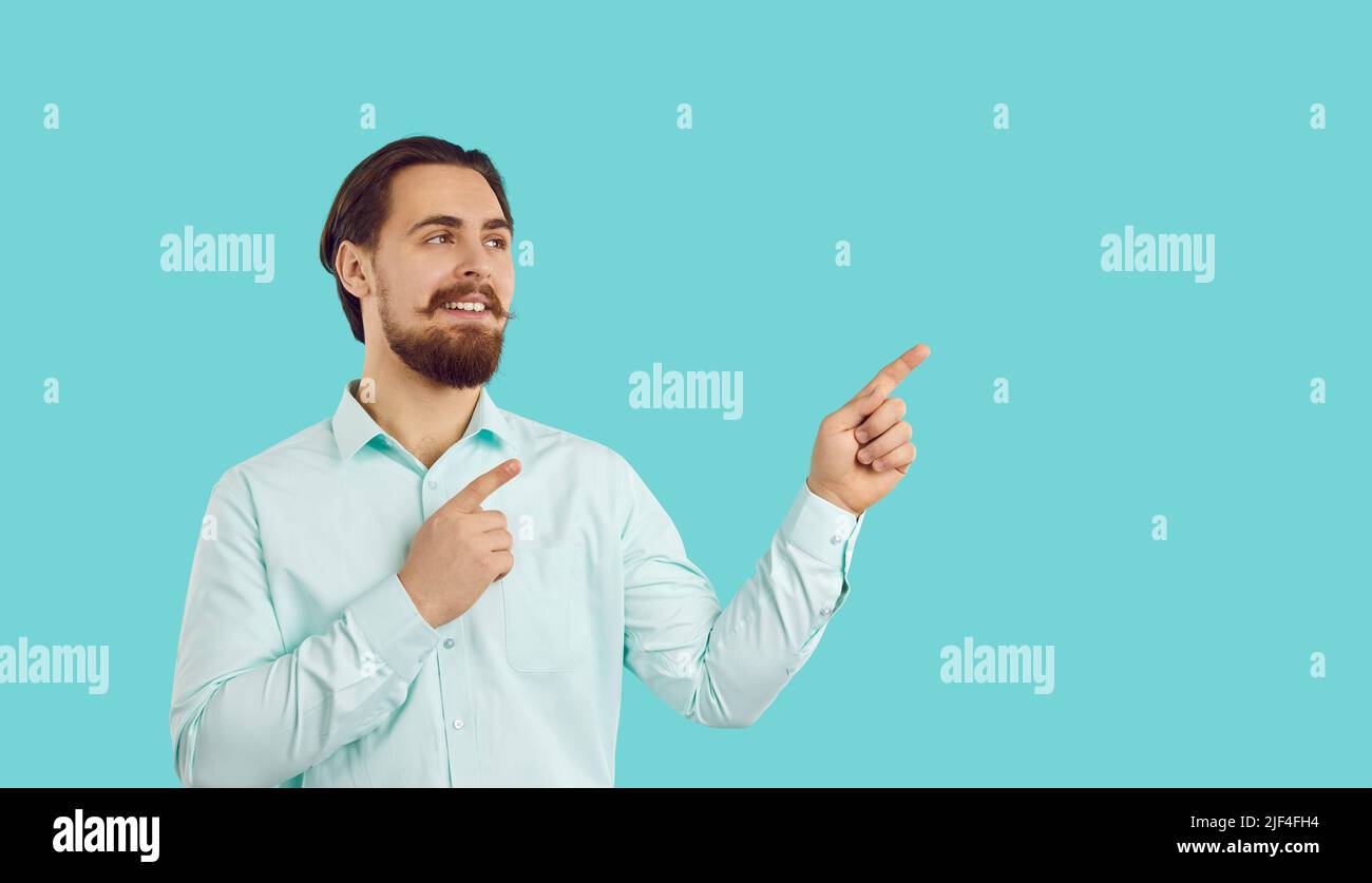 Happy male customer presenting new product, pointing finger at copy space on light blue background. Stock Photo