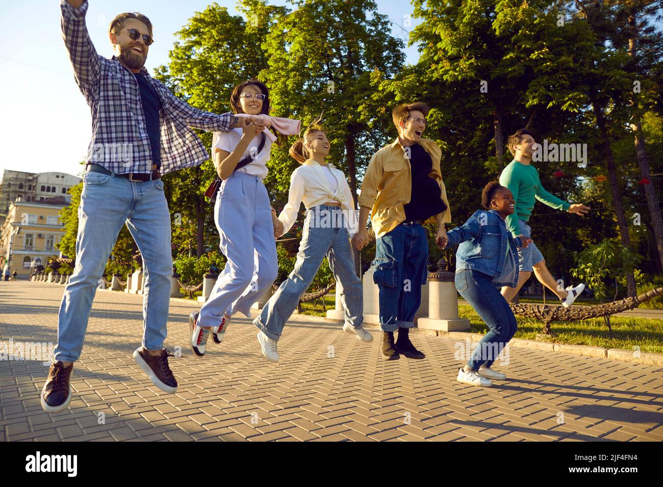 Happy excited multiethnic friends spending free time together, jumping and having fun Stock Photo