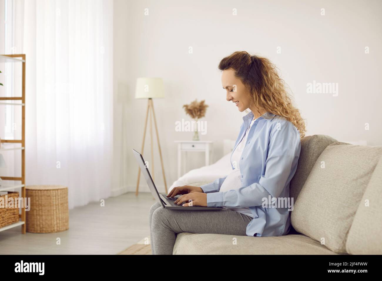 Smiling woman working online on computer at home Stock Photo