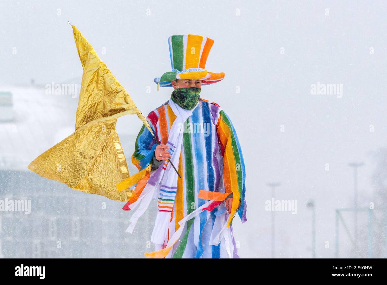 Minsk, Belarus - February 25, 2017: Animator at a sports festival dressed in rainbow colors with a golden flag Stock Photo