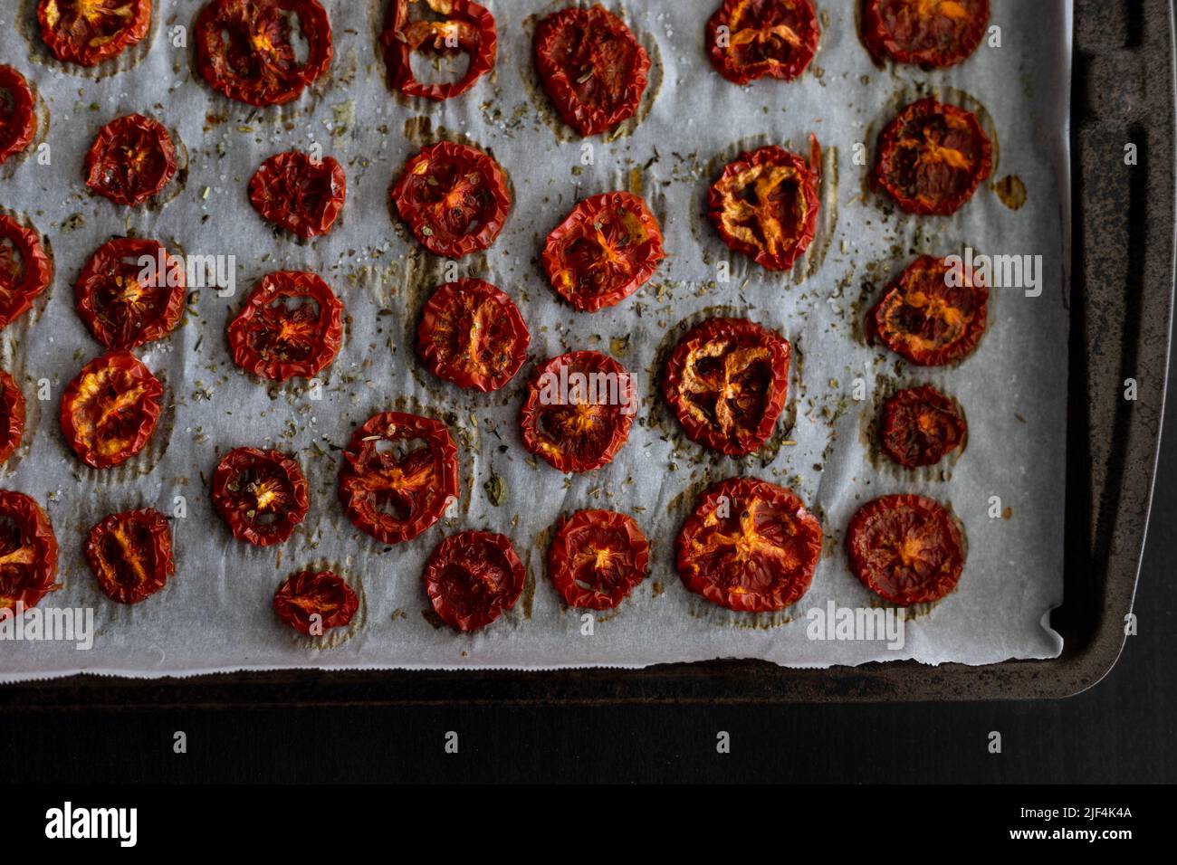 Freshly Dried Tomatoes with Herbs on Parchment Paper and Cookie Sheet Straight From the Oven Stock Photo