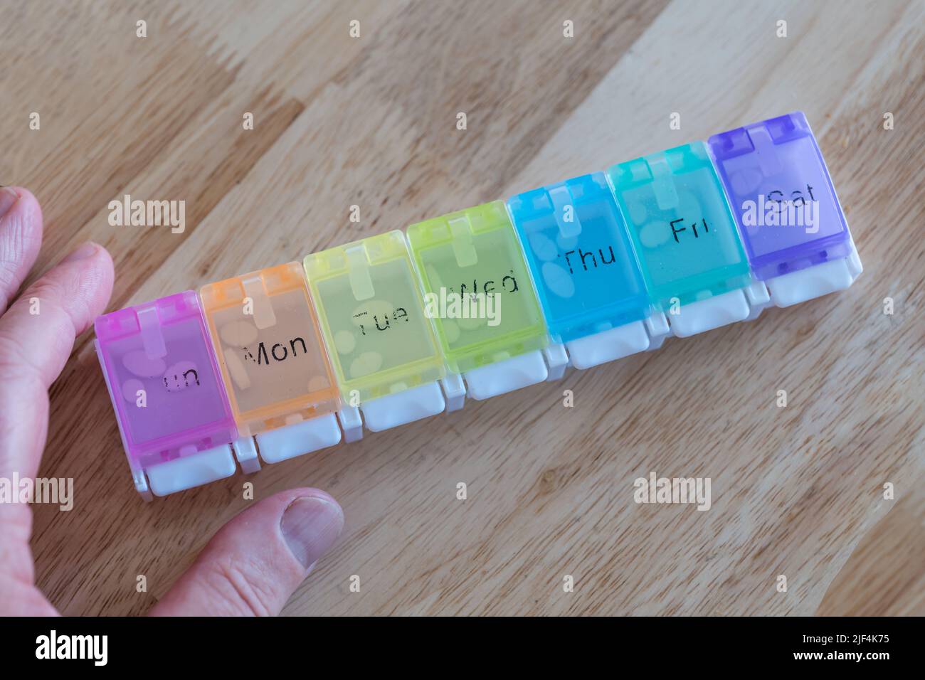 A man organising weekly medication tablets or pills in a pill organiser ...