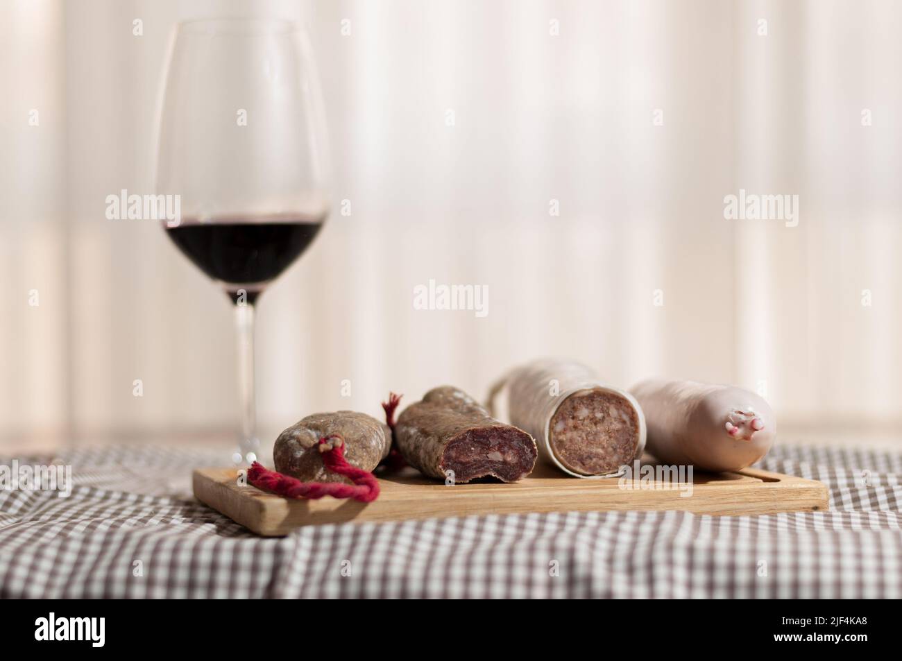 A glass of wine and some sausages to eat, with its background blur