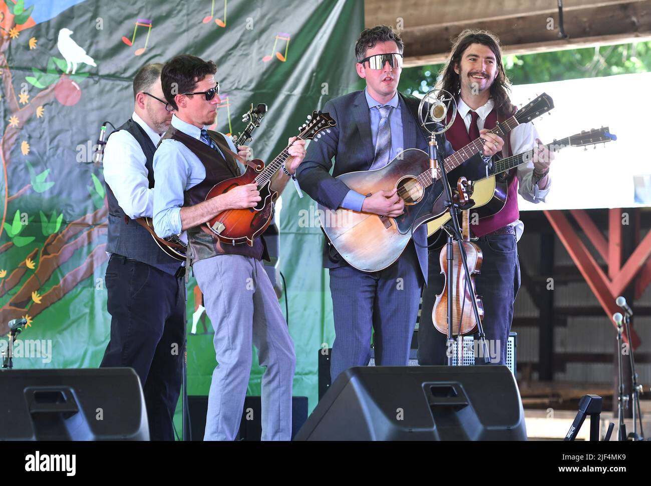 Band members of Poor Monroe, John Benjamin (mandolin), Eric Lee (guitar/fiddle), Sean Davis (guitar) are shown performing on stage during a “live” concert appearance at the Green River Festival. Stock Photo