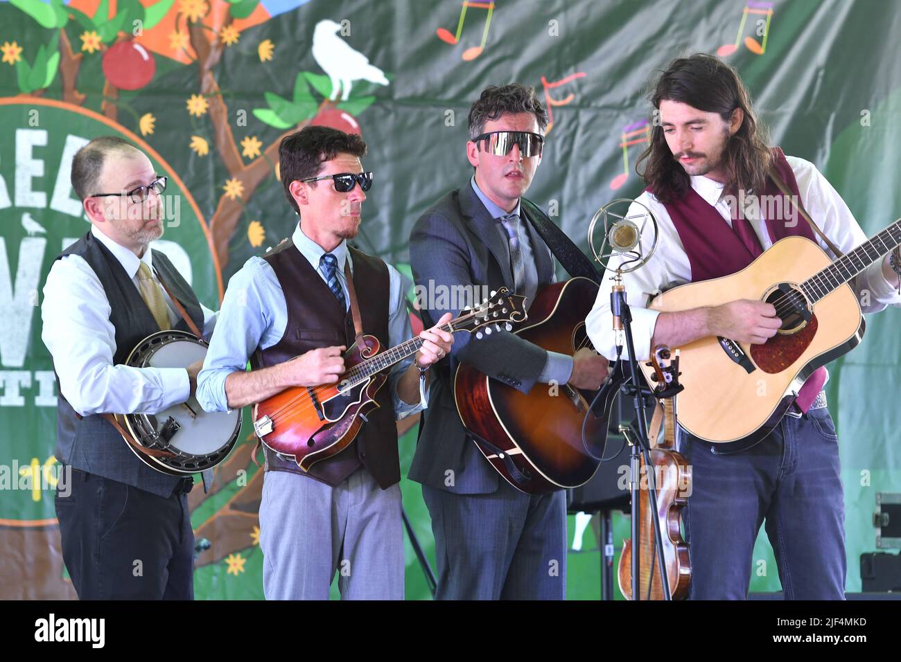 Band members of Poor Monroe, John Benjamin (mandolin), Eric Lee (guitar/fiddle), Sean Davis (guitar) are shown performing on stage during a “live” concert appearance at the Green River Festival. Stock Photo