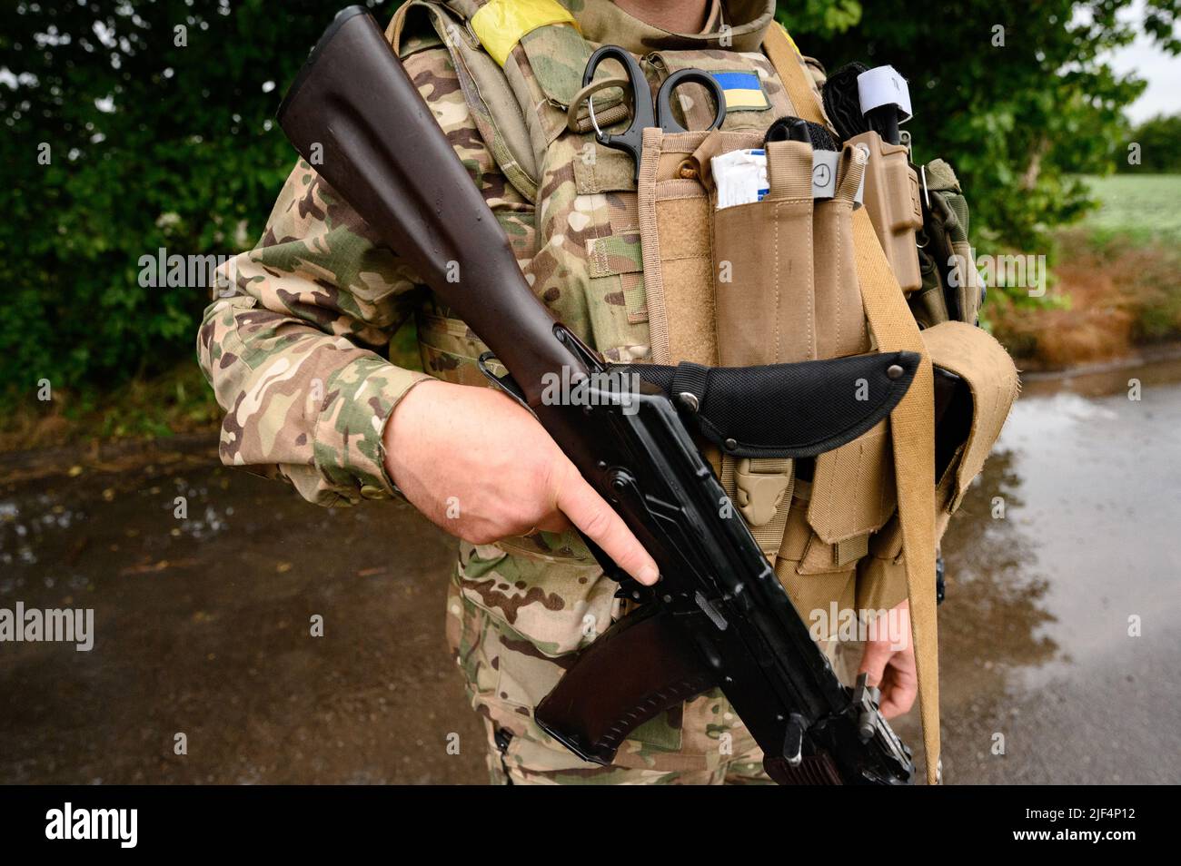 Military ammunition on a Ukrainian soldier with an assault rifle ak 74, bulletproof vest and medical turnstile. Stock Photo