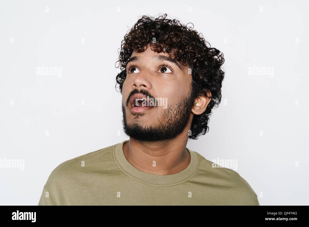 Young middle eastern man expressing surprise while looking upward isolated over white wall Stock Photo