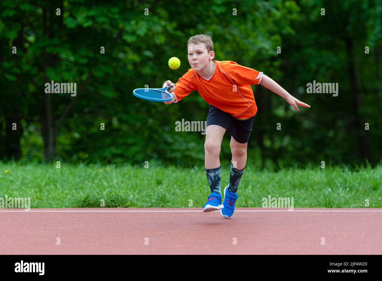 Child with tennis racket on tennis court. Training for young kid, healthy children. Horizontal sport theme poster, greeting cards, headers, website an Stock Photo
