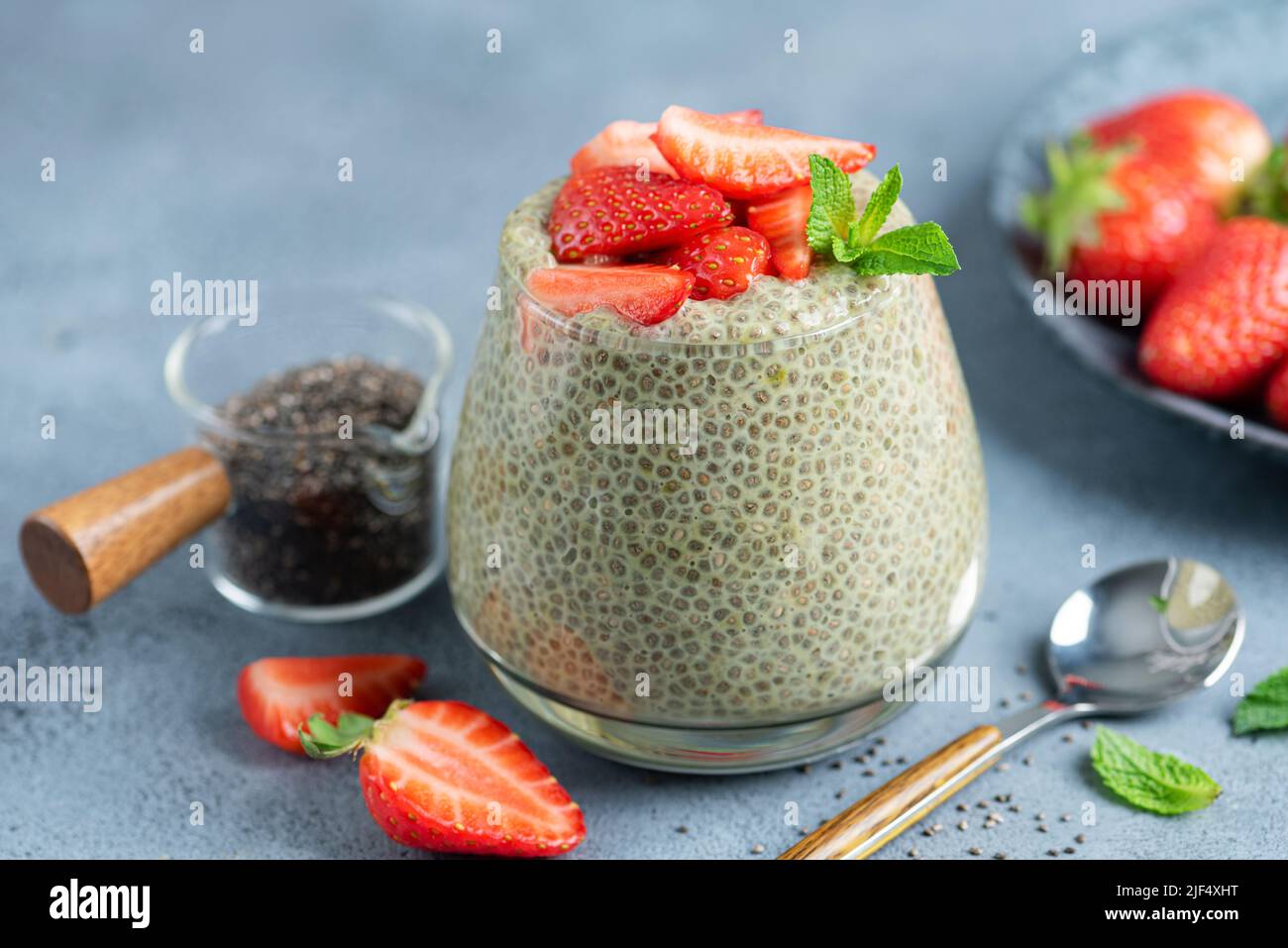 Chia pudding with strawberries in glass jar on blue stone background, closeup view Stock Photo