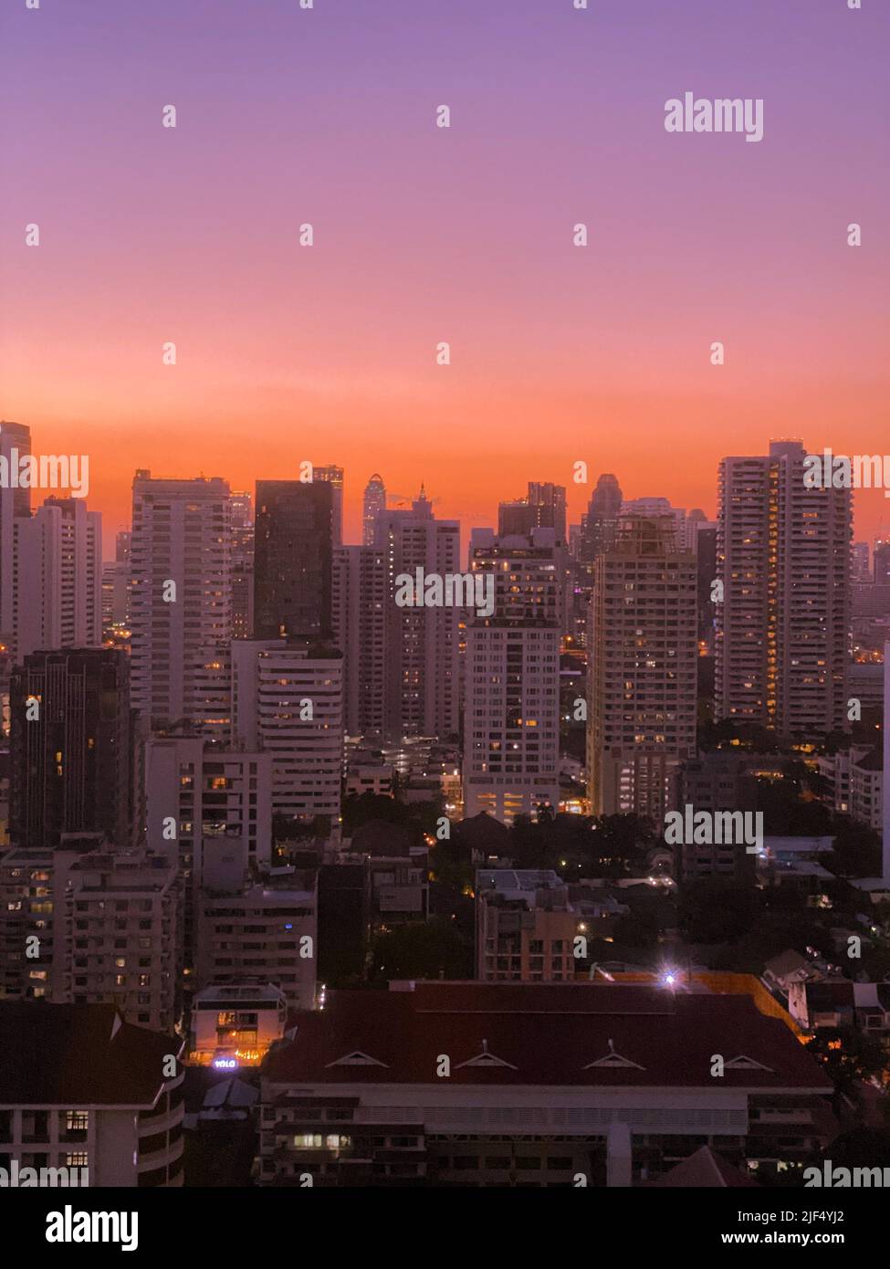 A vertical shot of urban landscape, pink clouds in sunset sky, above ...