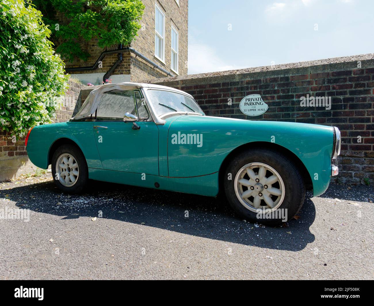 London, Greater London, England, June 15 2022: Classic convertible sports car in turquoise with a white roof in a private parking spot in Hammersmith. Stock Photo