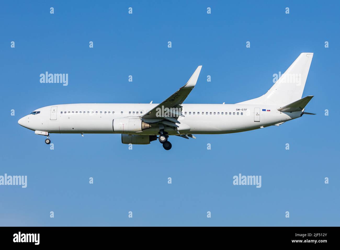 Full white neutralized airliner Boeing 737-800 of slovakian Carrier Air Explore landing at an airport in front of clear blue sky Stock Photo