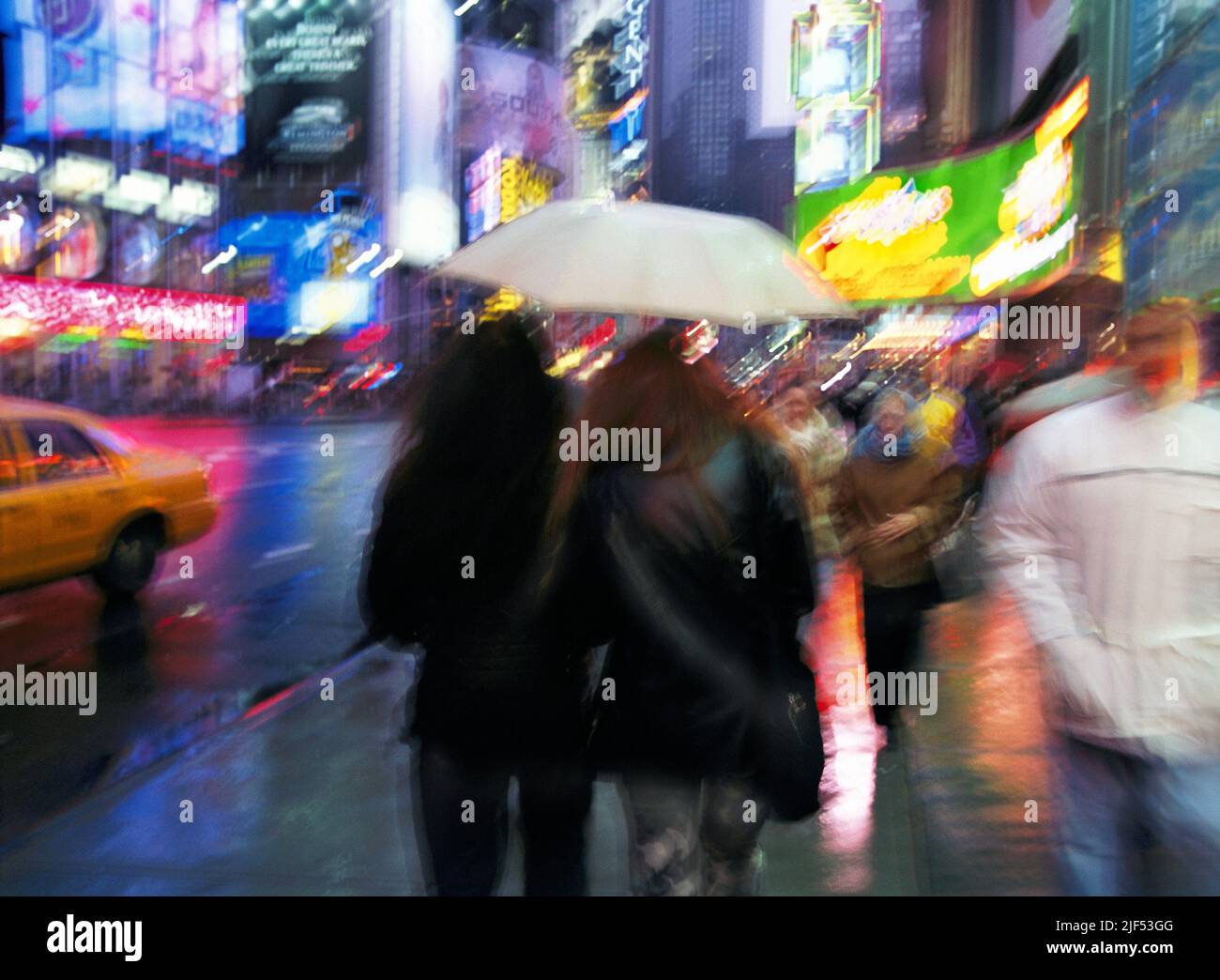 Broadway and Times Square on a rainy night, Midtown Manhattan, New York City with bright lights and a couple walking with an umbrella. USA Travel Stock Photo