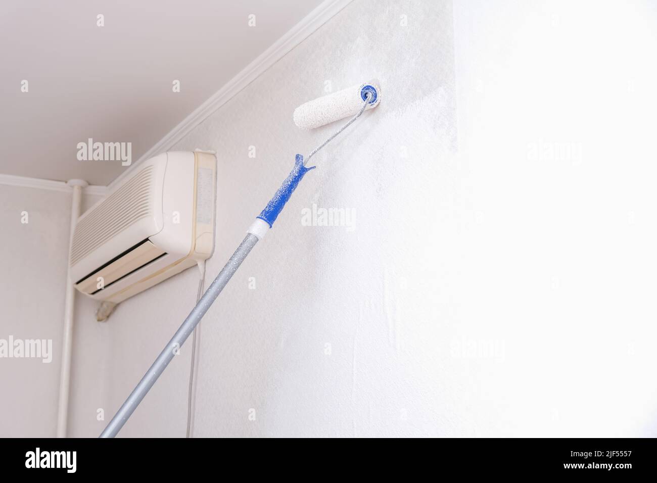 A man is painting vinyl wallpaper with a velour roller for painting
