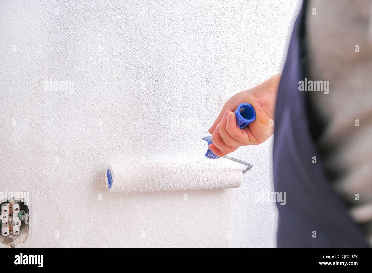 A man is painting vinyl wallpaper with a velour roller for painting