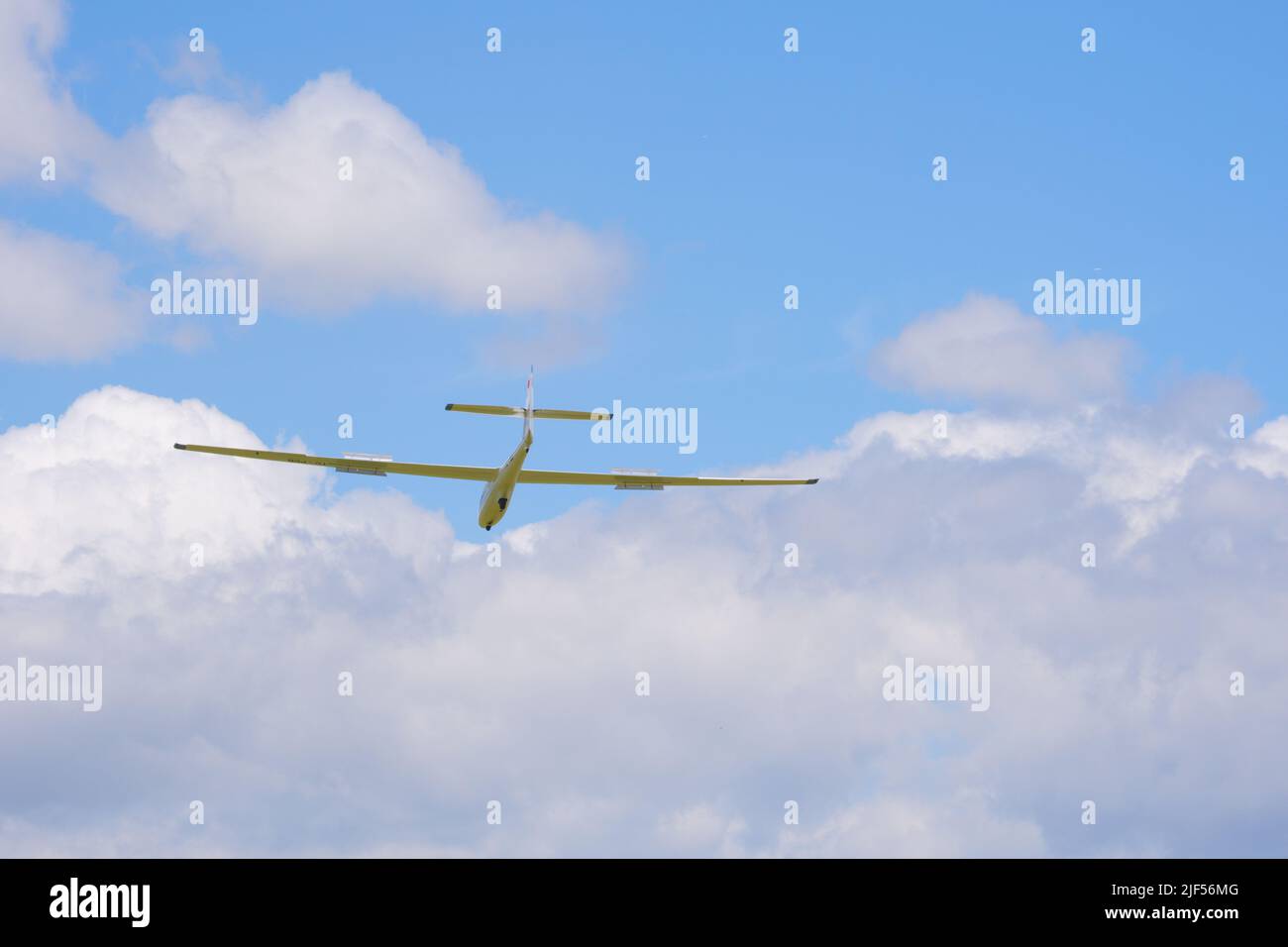 Glider flying high at blue sky with light clouds Stock Photo