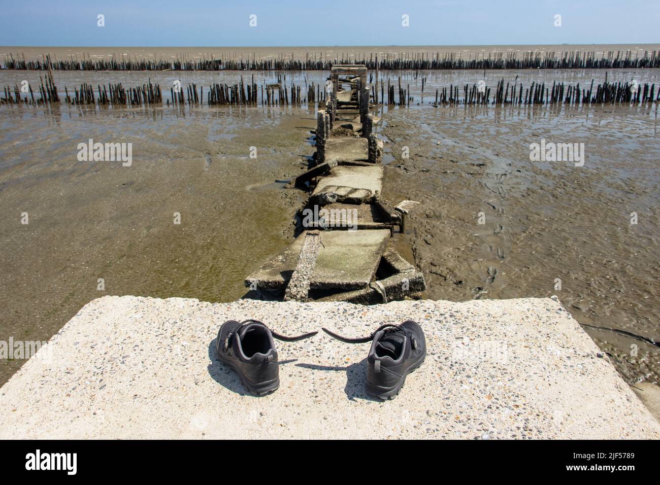 Abandoned shoes at the end of a demolished path with sea horizon. Stock Photo