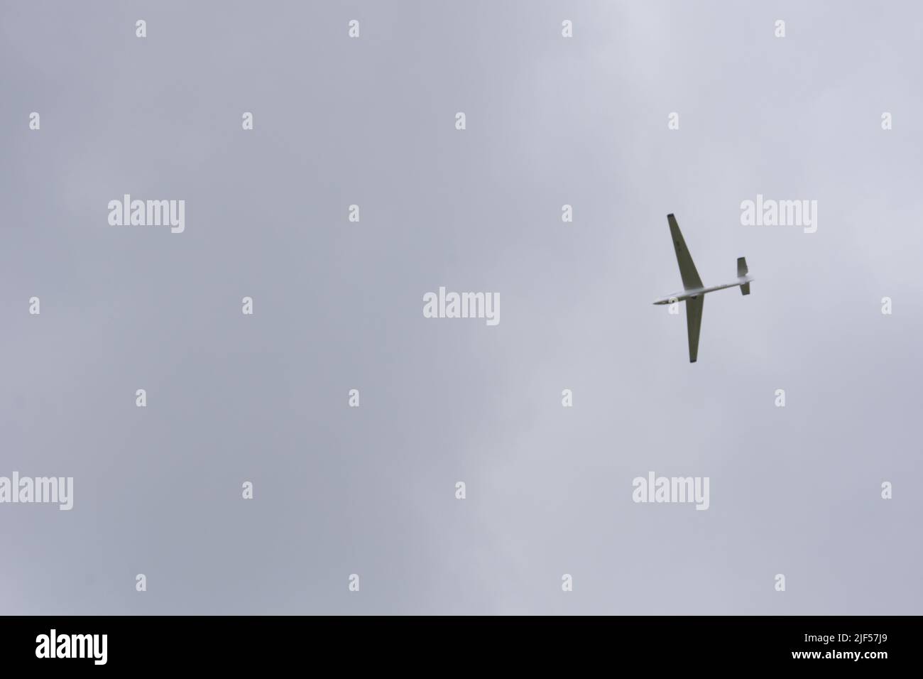 Glider flying high within dark clouds Stock Photo