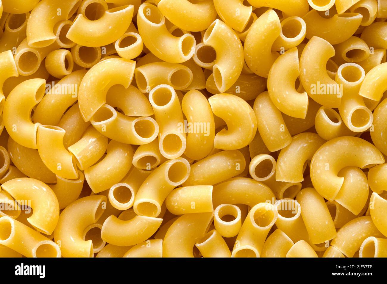 Dry Elbow Pasta Macaroni Noodles Pile Background. Stock Photo
