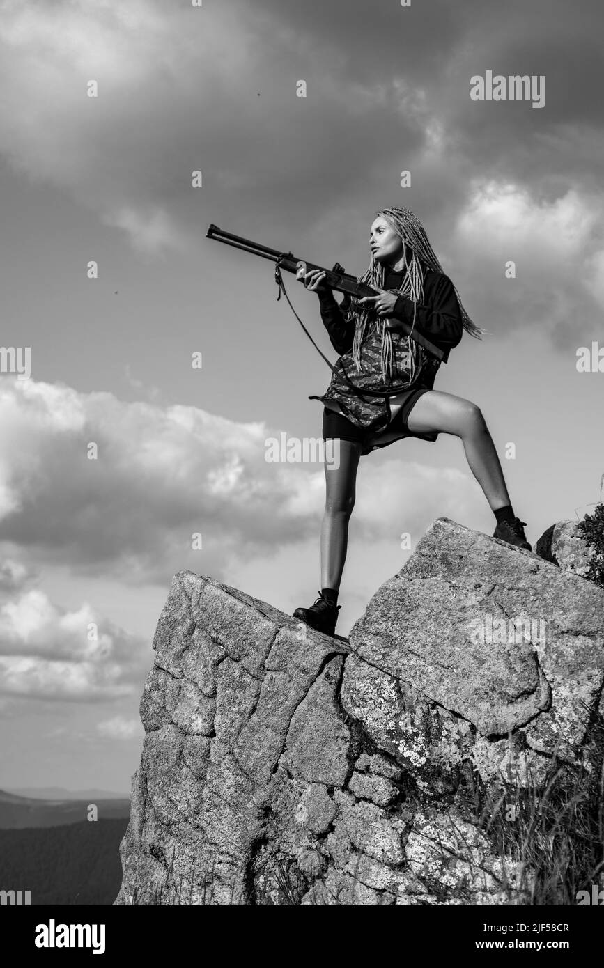 Female with a gun. Woman hunter with a gun. Calibers of hunting rifles. Hunter with a shotgun in a traditional shooting clothing. Outdoors active Stock Photo