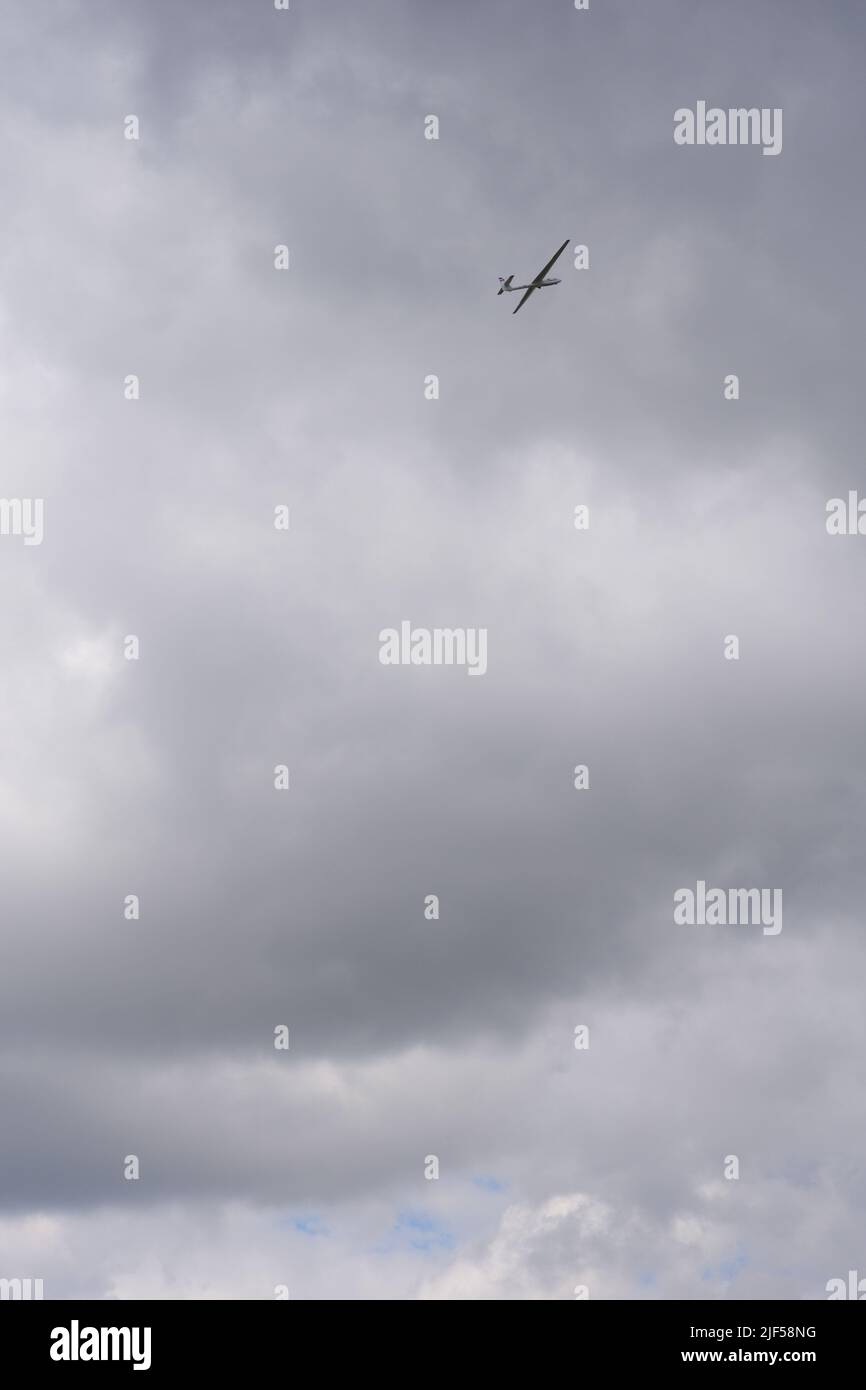 Glider flying high within dark clouds Stock Photo