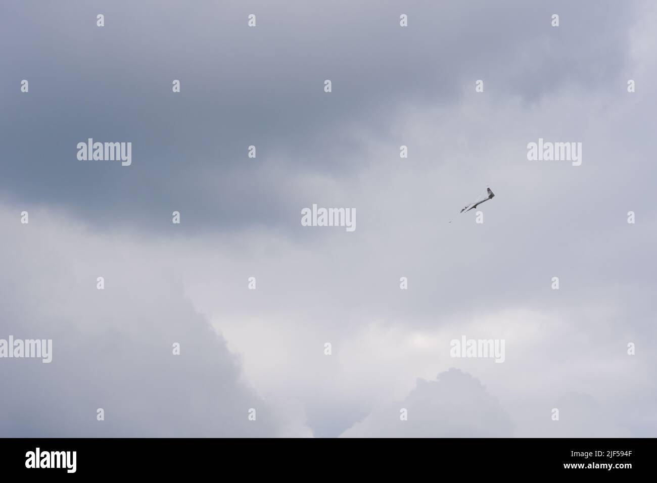 Glider flying high within dark clouds Stock Photo
