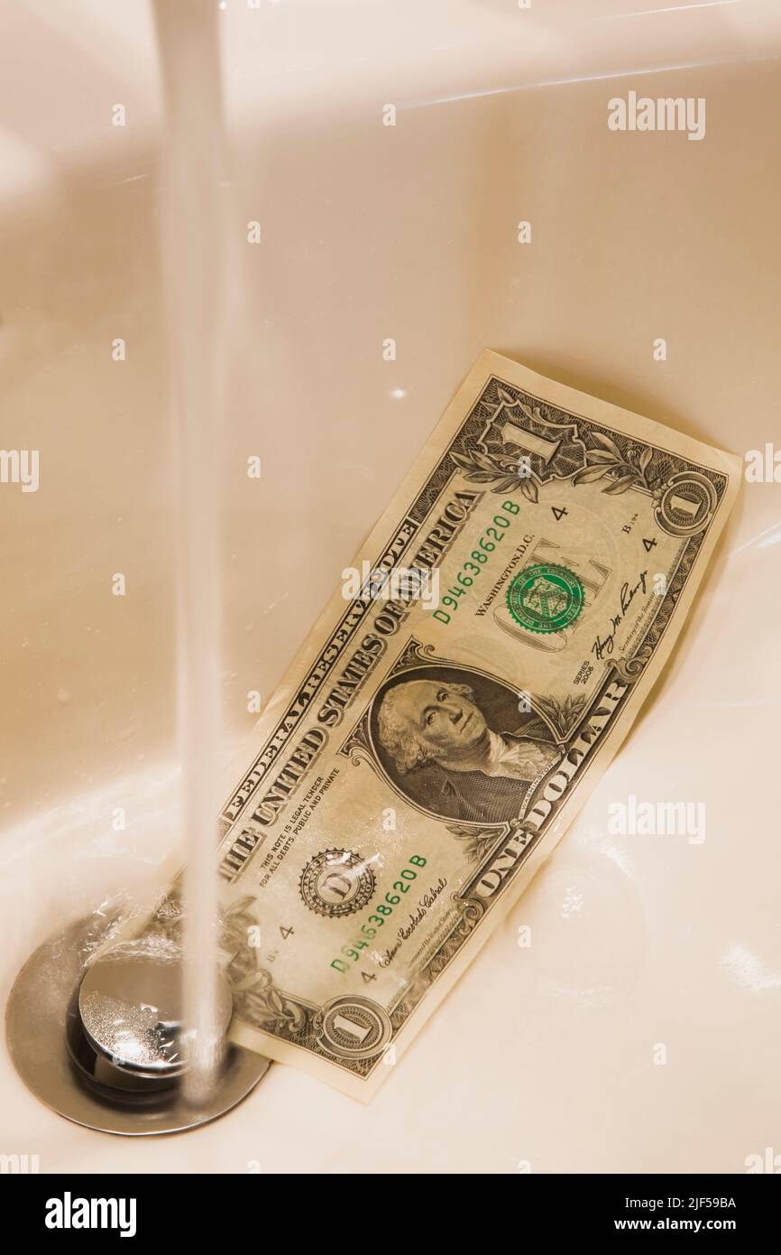 US dollar going down the drain in sink. Stock Photo