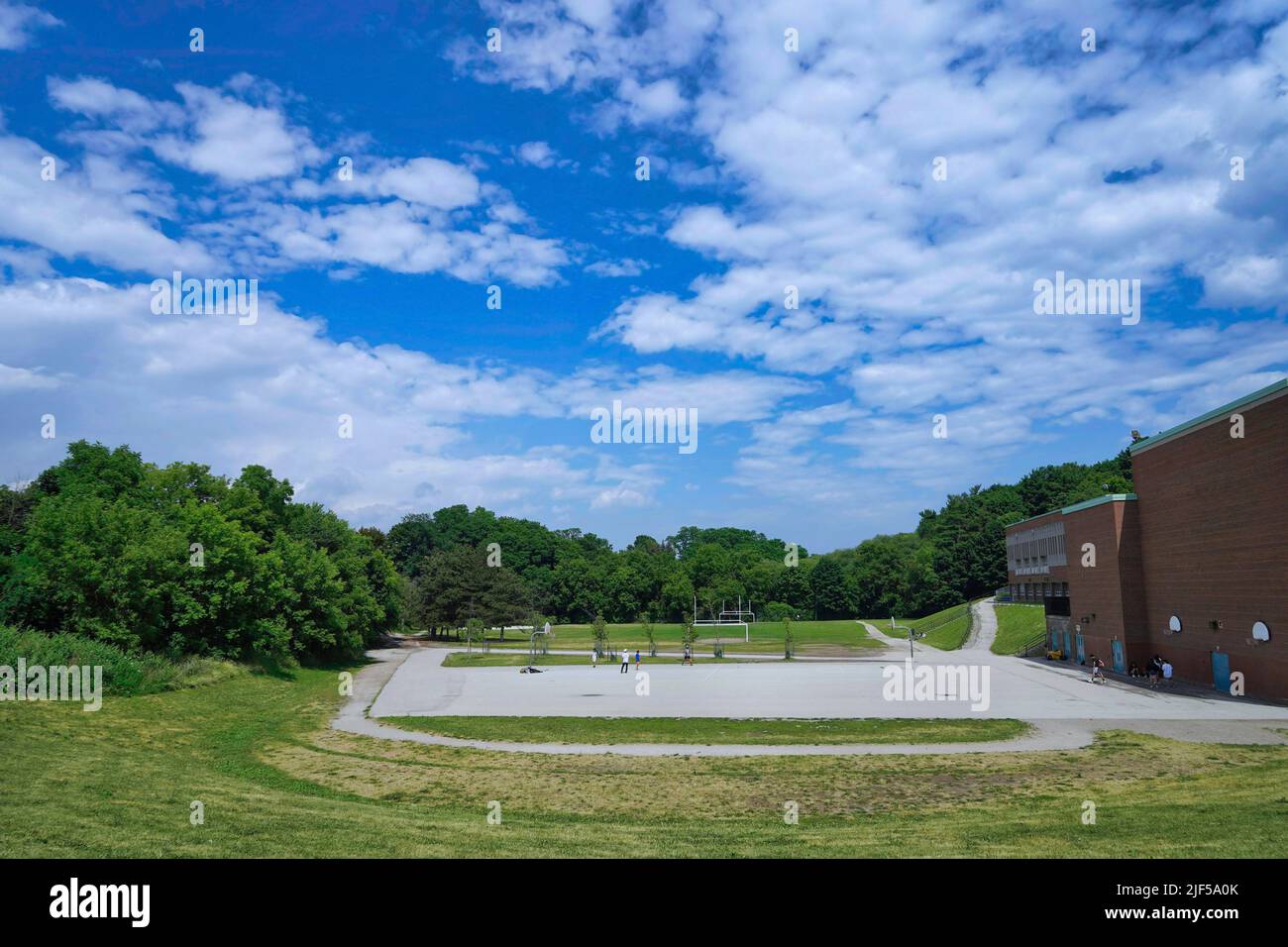 Sports field beside a school, surrounded by trees Stock Photo