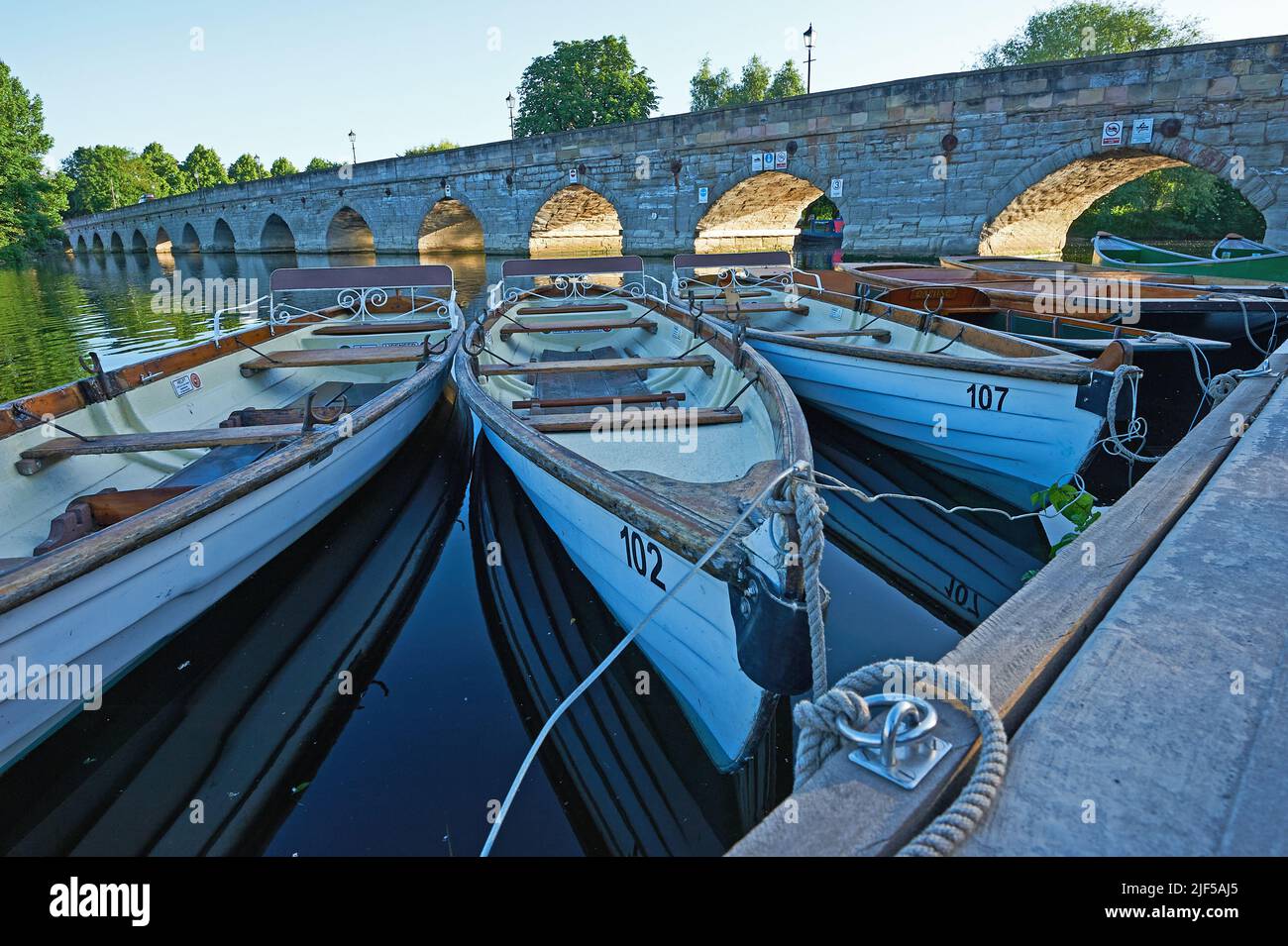 Day hire rowing boats moored on the River Avon at Stratford upon Avon, with Clopton Bridge in the background. Stock Photo