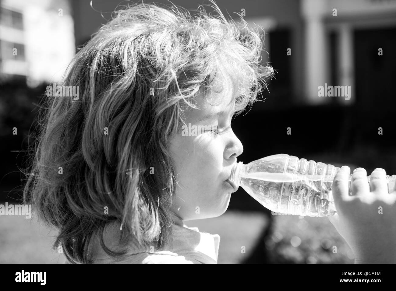 Portrait of a cute child boy drinking water from bottle. Close up caucasian kids face. Closeup head of funny kid. Stock Photo