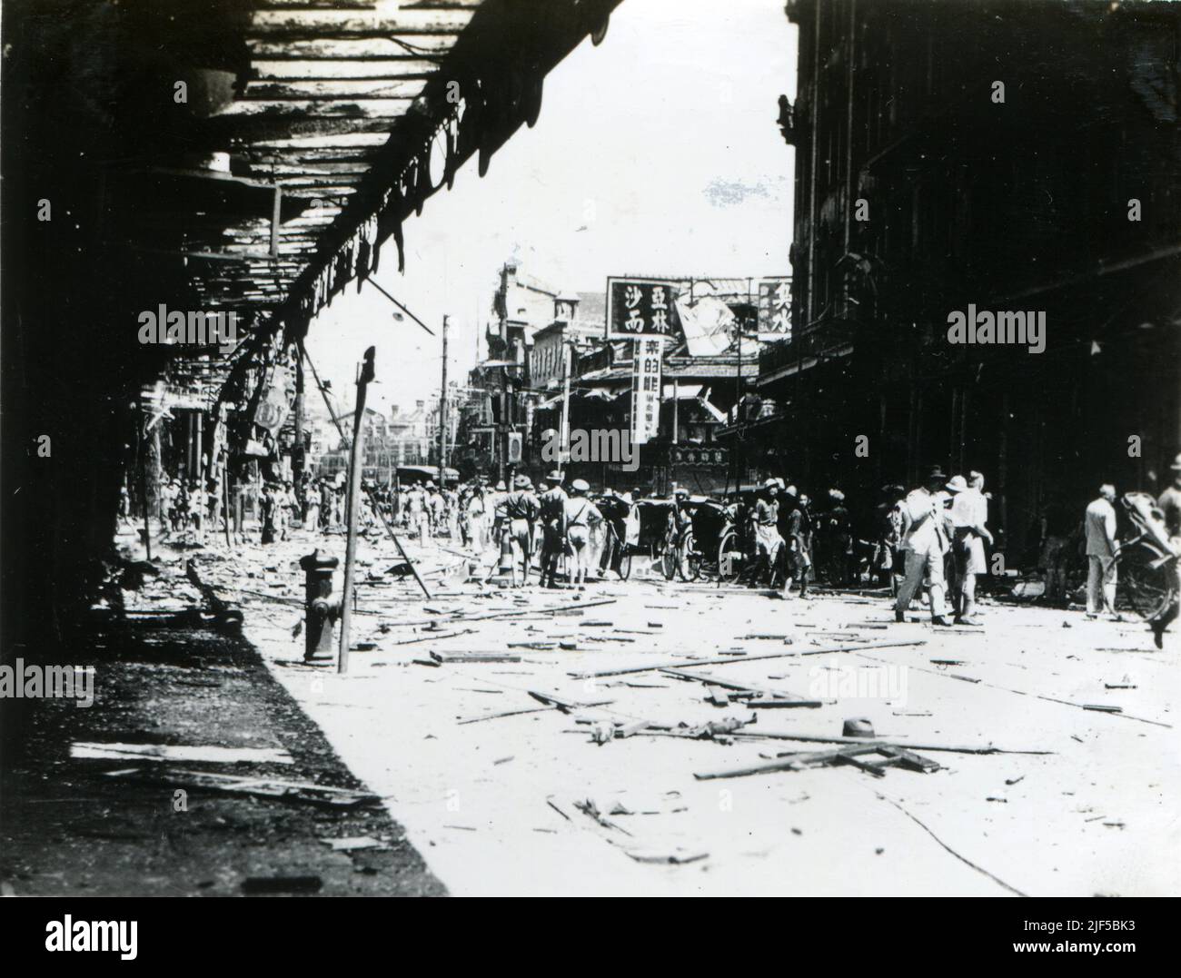 Nanking Road (Nanjing Road) after air raid during the Japanese invasion of Shanghai in 1937, showing damaged buildings and people on the street. Stock Photo