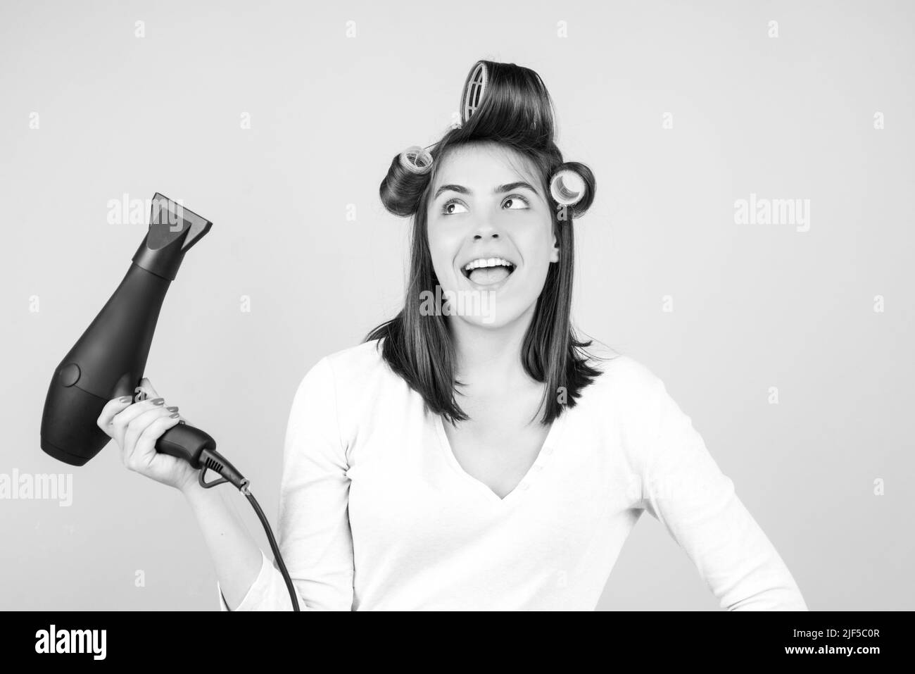 Amazed woman with hair dryer. Excited girl with straight hair drying hair with professional