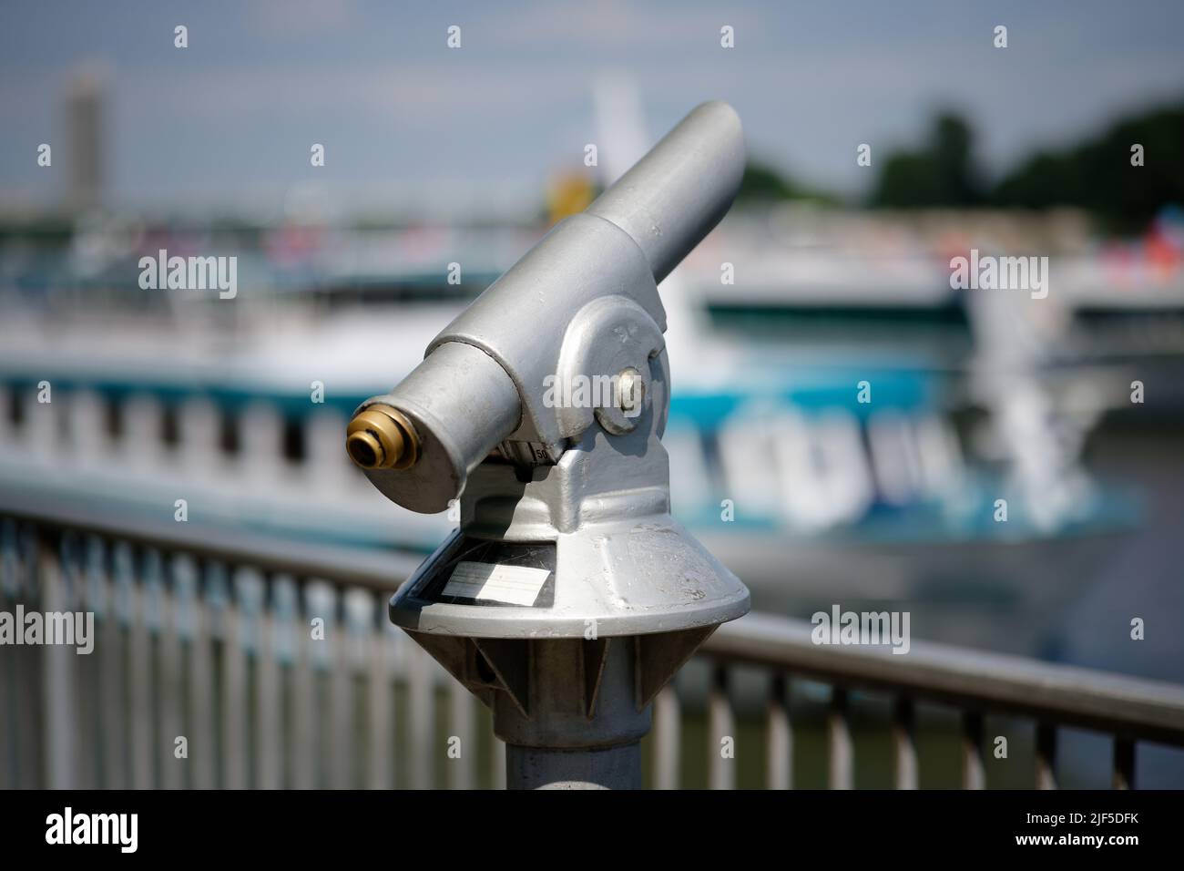 coin telescope on a river bank with ships in blurred background Stock Photo
