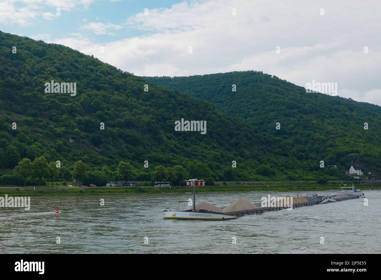 A flat-bottomed river barge, the Independent II, transports sand and gravel through the Middle Rhine in the Rhineland-Palatinate district of Germany. Stock Photo