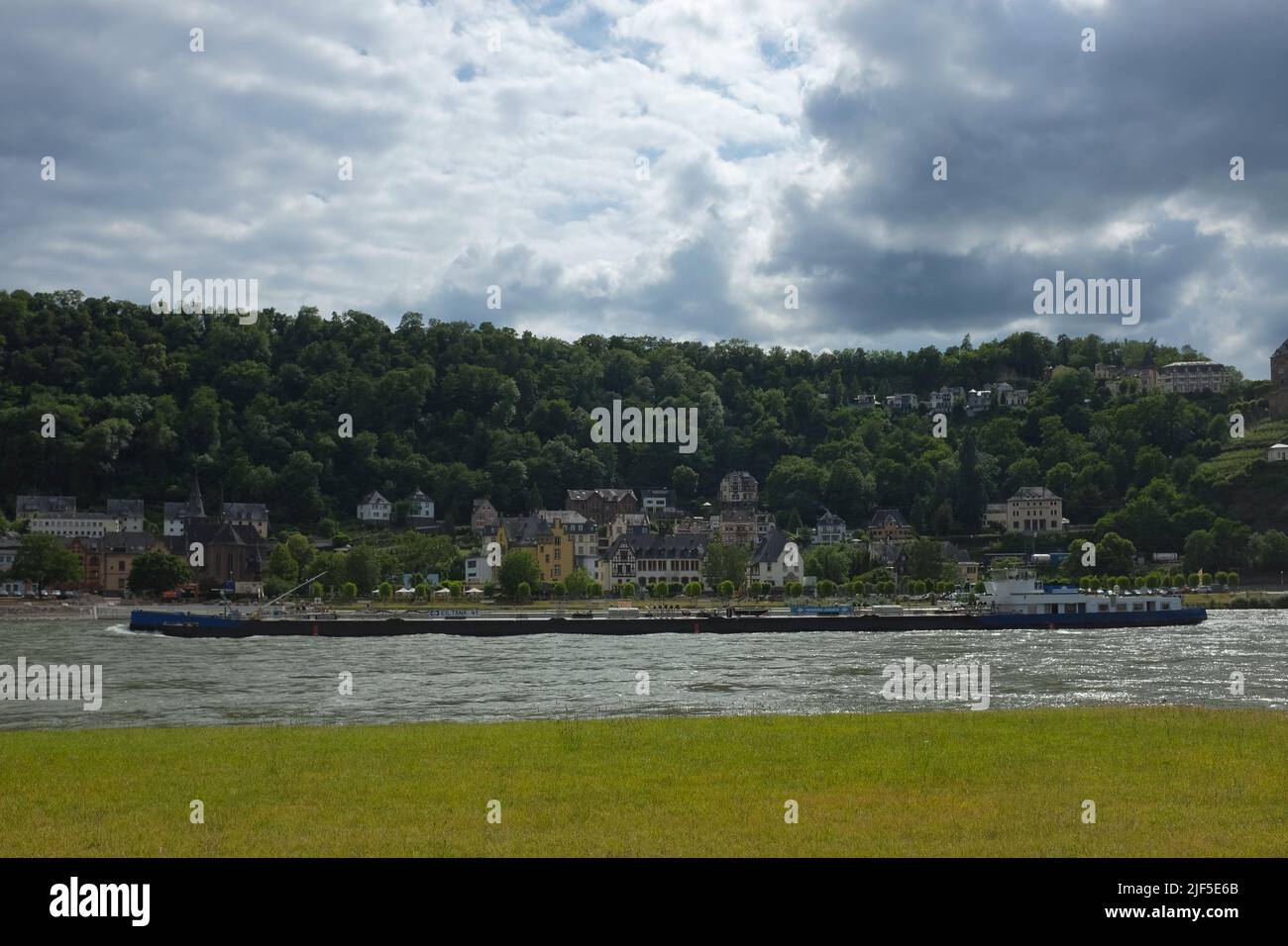 Long and narrow Reederei Jaegers flat-bottomed ship transport goods through the Middle Rhine, along St. Goar in Rhineland-Palatinate, Germany. Stock Photo