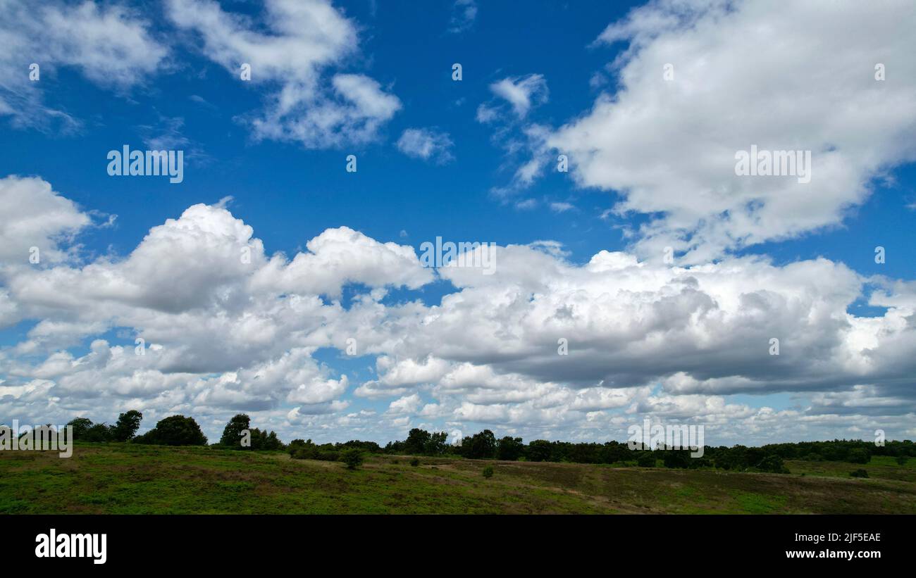 A bright blue sky with fluffy white clouds over a field Stock Photo - Alamy