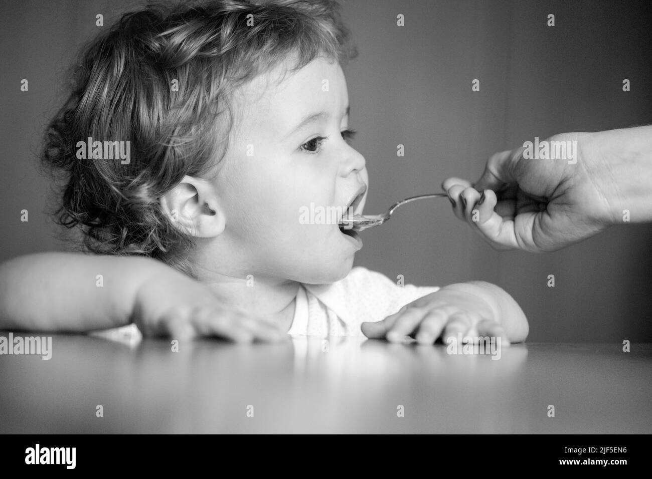 Spoon feeding baby. Mother giving healthy food to her adorable child at ...