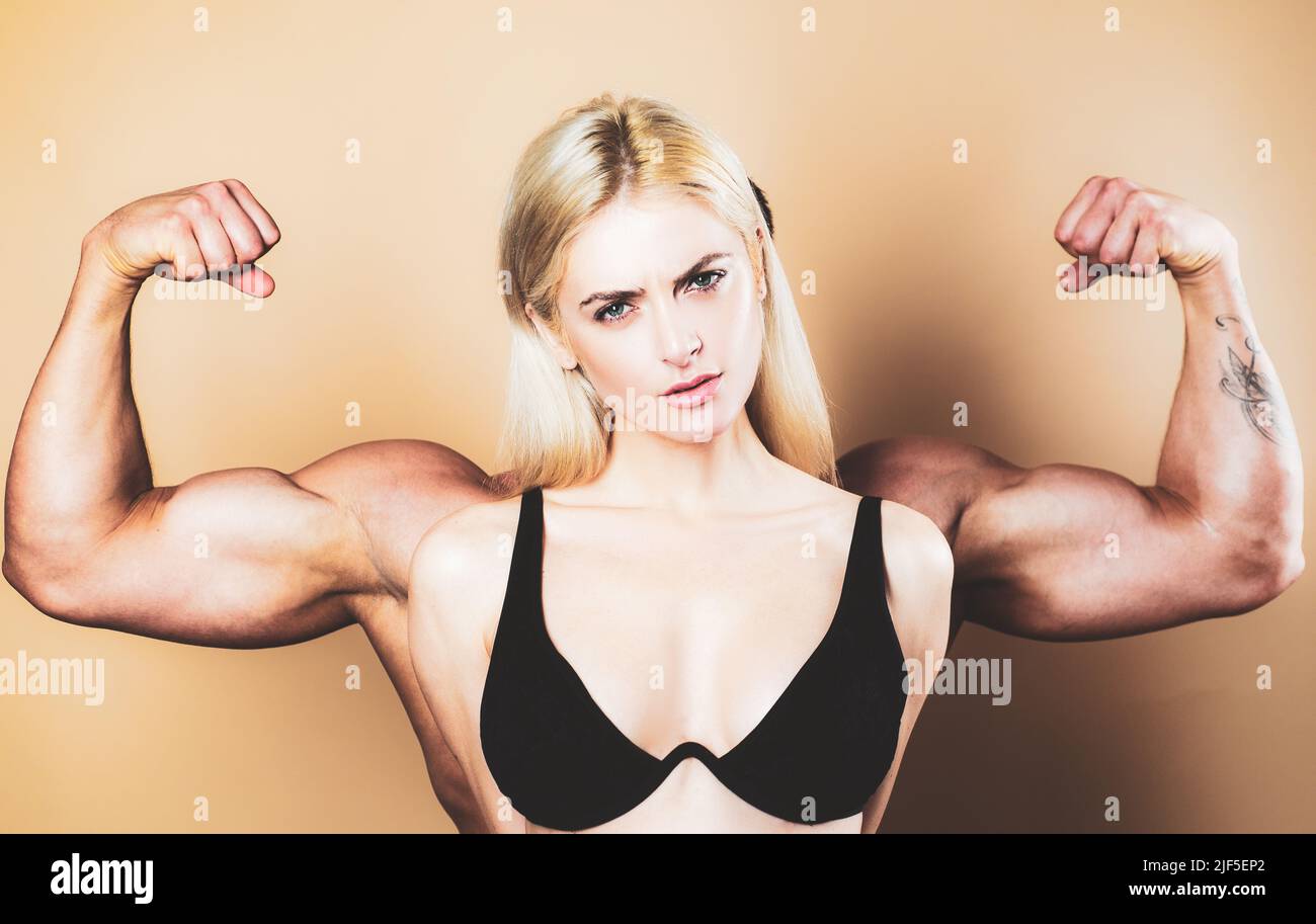 Funny fitness couple. Funky girl have bodybuilding practice, show biceps. A young female model posing with male big muscles. Fun fitness. Woman power Stock Photo
