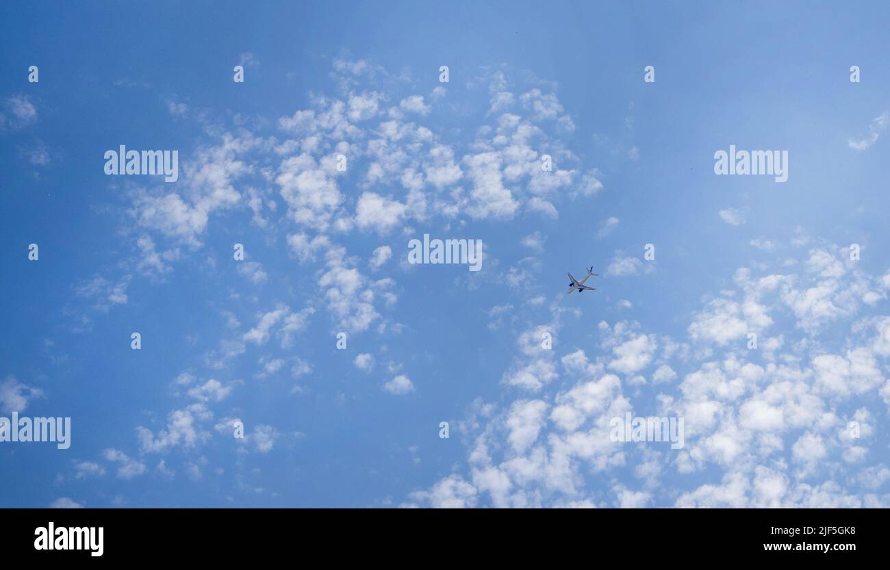 The plane is flying in a blue sky among clouds and sunlight, a copy of ...