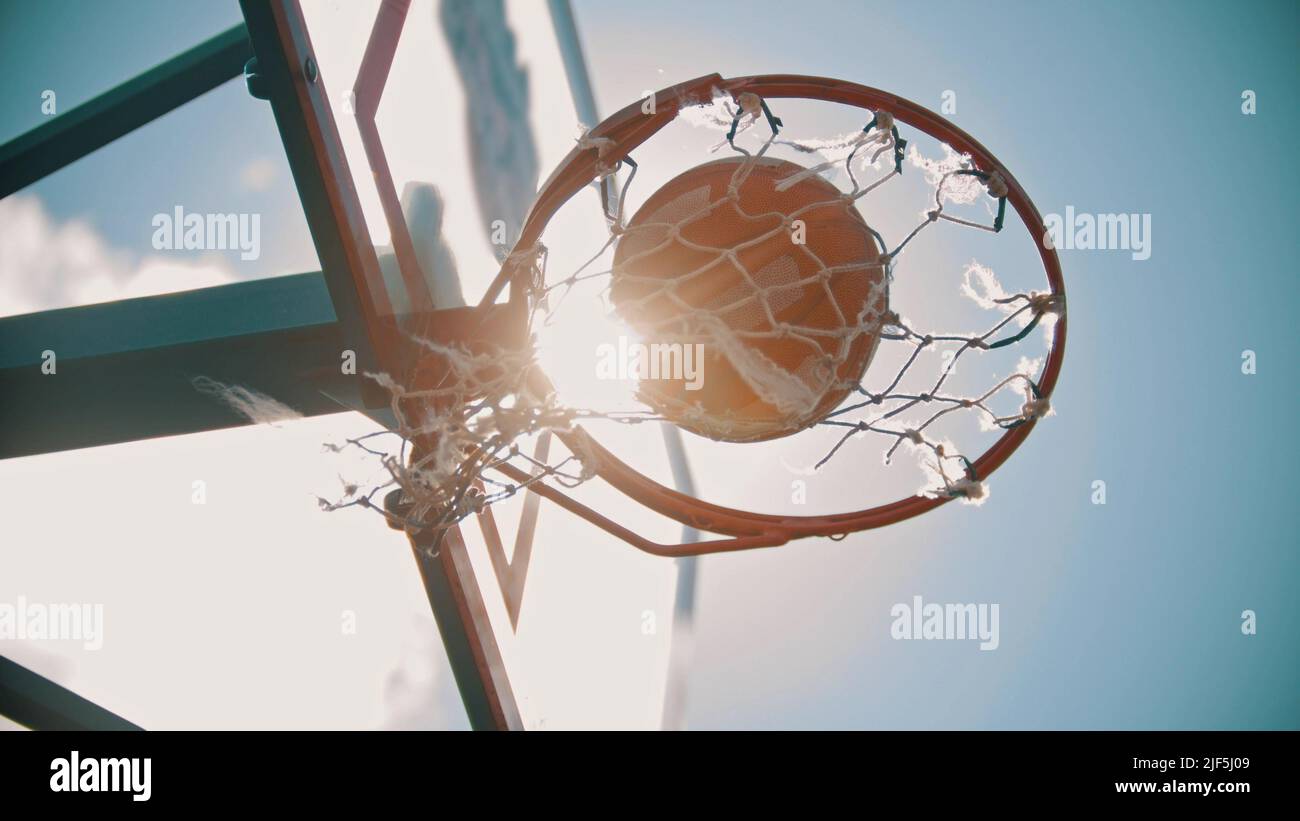 A basketball hoop. A ball gets in the target. Bright sunlight. View from the bottom Stock Photo
