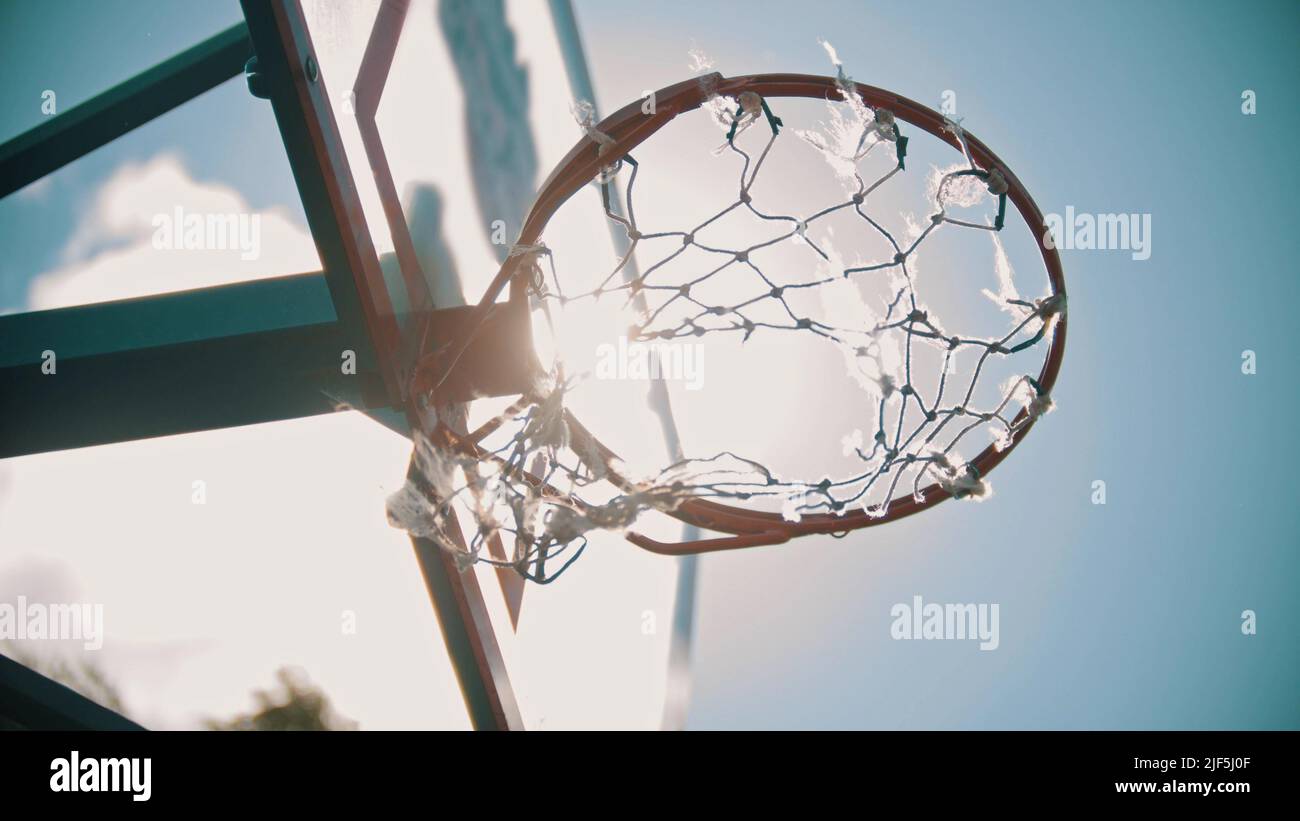 A basketball hoop. The net fluttering on the wind. Bright sunlight. View from the bottom Stock Photo